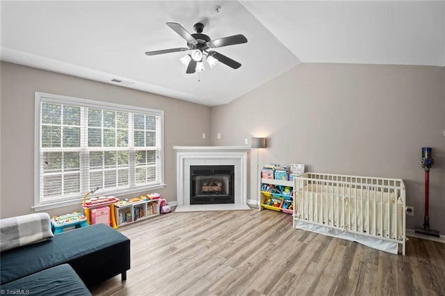 living area featuring a ceiling fan, baseboards, wood finished floors, lofted ceiling, and visible vents