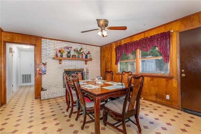 2003 Random Dr, Greensboro, NC 27407 - dining space featuring light floors, wood walls, a ceiling fan, a brick fireplace, and crown molding