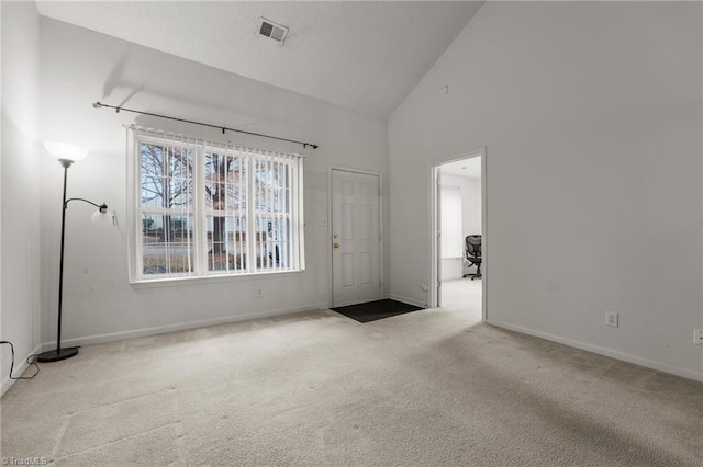 carpeted spare room featuring high vaulted ceiling