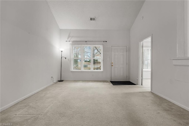 carpeted spare room with high vaulted ceiling