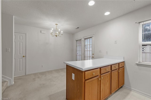 kitchen with an inviting chandelier, hanging light fixtures, a textured ceiling, light colored carpet, and kitchen peninsula