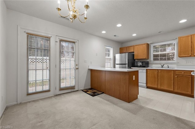 kitchen with kitchen peninsula, light carpet, dishwasher, stainless steel refrigerator, and hanging light fixtures