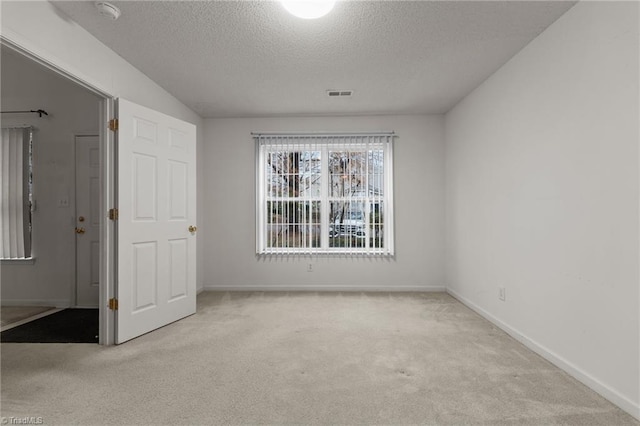 carpeted empty room with a textured ceiling