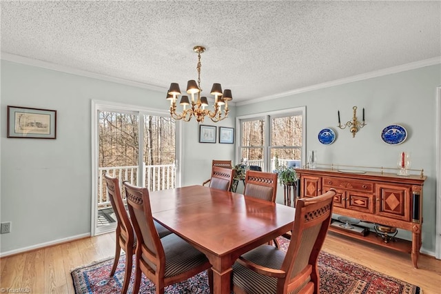 dining space with light wood-type flooring, ornamental molding, a chandelier, and a textured ceiling