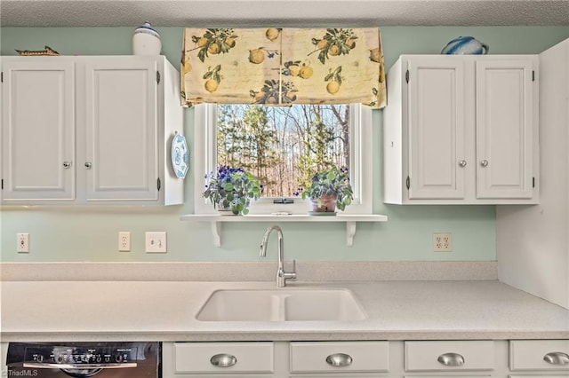 kitchen with dishwashing machine, white cabinets, a sink, and light countertops