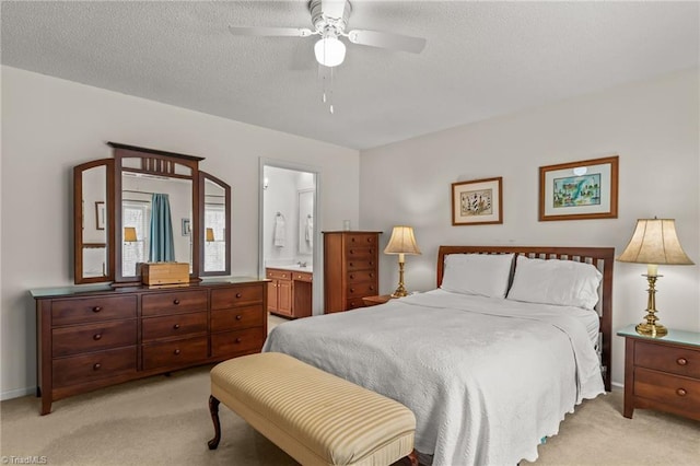 bedroom featuring a textured ceiling, baseboards, ensuite bath, and light colored carpet