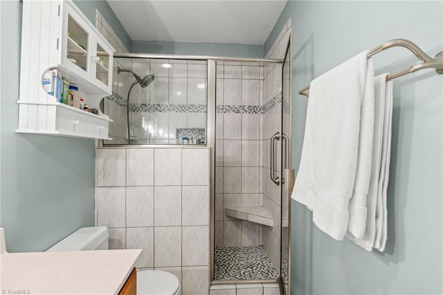 bathroom featuring a textured ceiling, a stall shower, vanity, and toilet