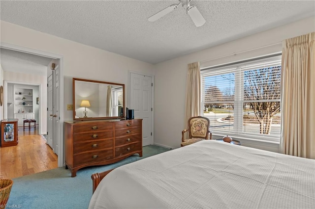 carpeted bedroom featuring a textured ceiling and a ceiling fan