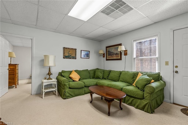 living room featuring visible vents, a drop ceiling, and carpet flooring