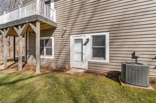 doorway to property featuring a lawn, a deck, and cooling unit