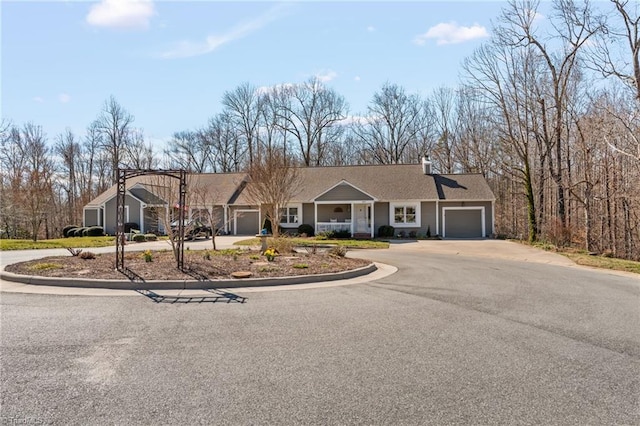 single story home featuring covered porch, driveway, a chimney, and an attached garage