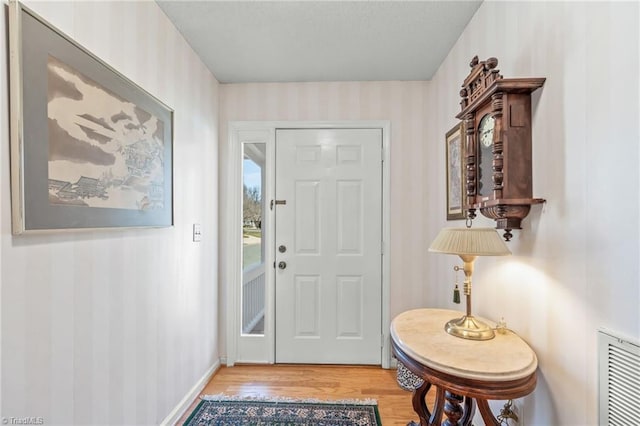 foyer entrance with visible vents, baseboards, and wood finished floors