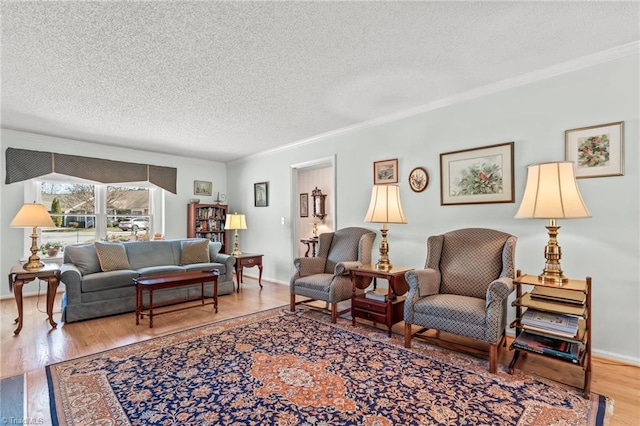 living area featuring ornamental molding, a textured ceiling, baseboards, and wood finished floors