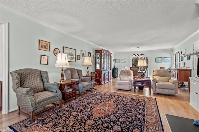 living room featuring a notable chandelier, crown molding, light wood-style flooring, and a textured ceiling