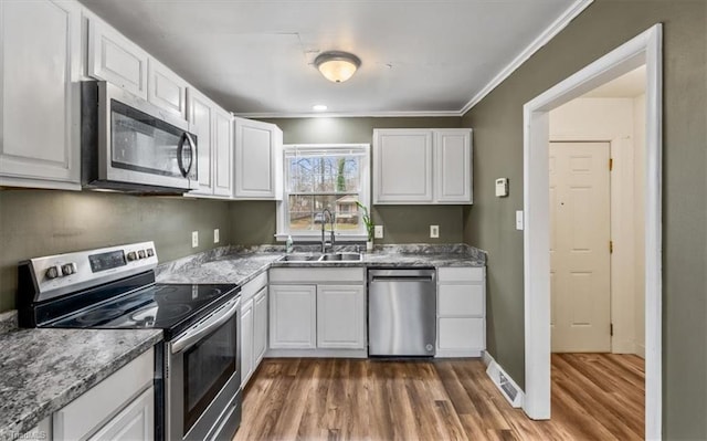 kitchen featuring sink, appliances with stainless steel finishes, white cabinetry, dark hardwood / wood-style floors, and ornamental molding