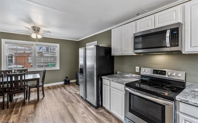 kitchen featuring crown molding, light stone counters, light wood-type flooring, appliances with stainless steel finishes, and white cabinets