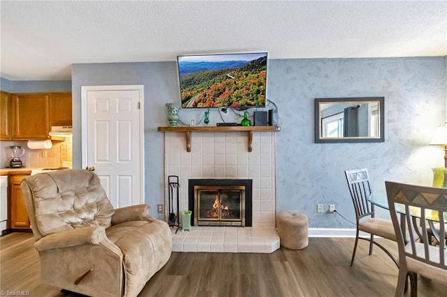 living area featuring a textured ceiling, light hardwood / wood-style floors, and a fireplace