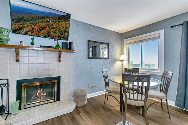 dining area featuring a tile fireplace and hardwood / wood-style flooring