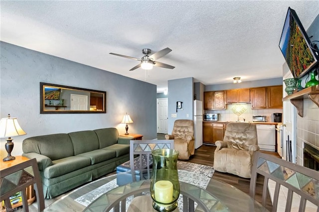 living room featuring ceiling fan, a fireplace, and a textured ceiling