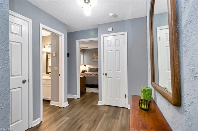 corridor with hardwood / wood-style floors and a textured ceiling