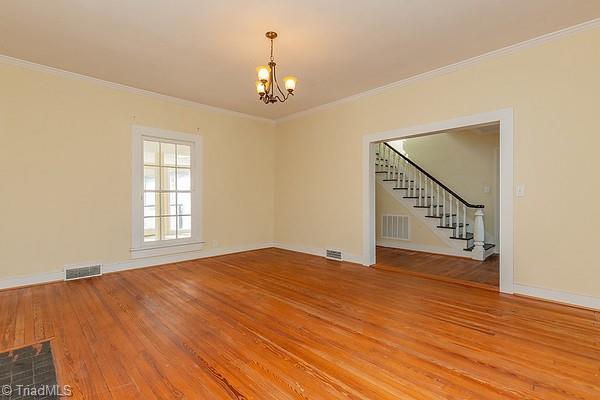 112 S Caldwell St, Salisbury, NC 28144 - unfurnished room with a chandelier, stairs, light wood-style floors, ornamental molding, and baseboards