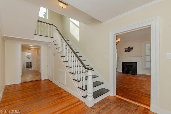 112 S Caldwell St, Salisbury, NC 28144 - stairs featuring wood finished floors, crown molding, and a fireplace with flush hearth