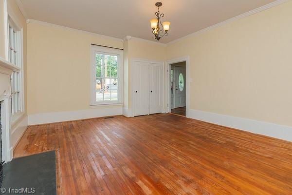 112 S Caldwell St, Salisbury, NC 28144 - empty room featuring crown molding, a chandelier, wood-type flooring, a fireplace, and baseboards