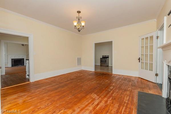 112 S Caldwell St, Salisbury, NC 28144 - unfurnished living room with a fireplace, a chandelier, ornamental molding, hardwood / wood-style floors, and baseboards