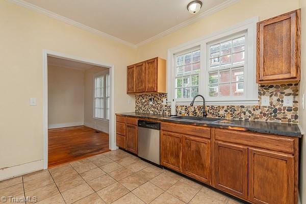 112 S Caldwell St, Salisbury, NC 28144 - kitchen featuring stainless steel dishwasher, a sink, crown molding, brown cabinets, and dark countertops