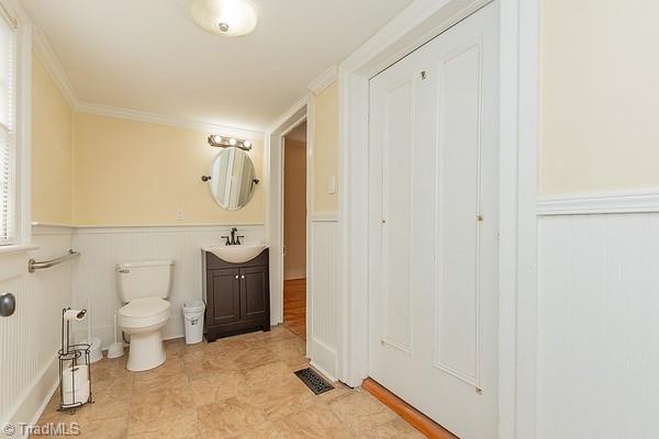 112 S Caldwell St, Salisbury, NC 28144 - bathroom with vanity, toilet, wainscoting, a decorative wall, and crown molding