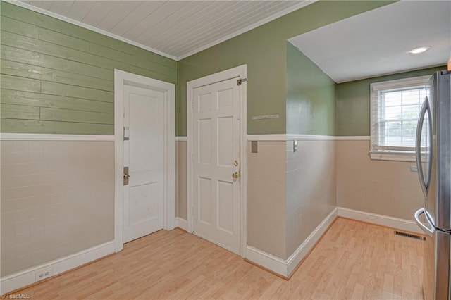 interior space with wainscoting, light wood-style flooring, visible vents, and ornamental molding