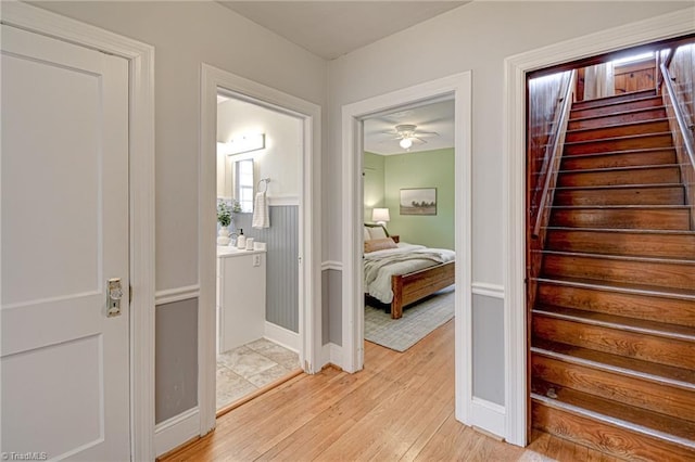 corridor featuring stairway, baseboards, and light wood-style flooring