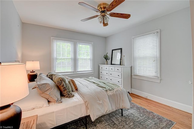 bedroom featuring baseboards, wood finished floors, and ceiling fan