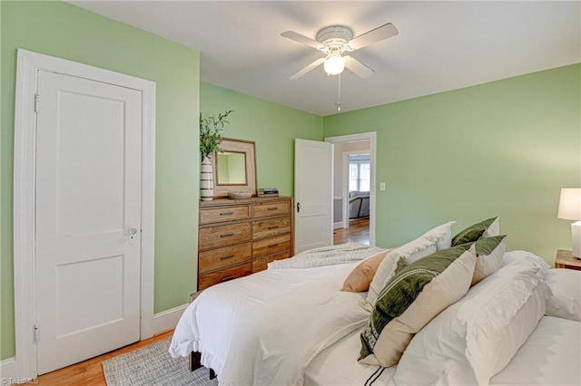 bedroom with ceiling fan, baseboards, and light wood-type flooring