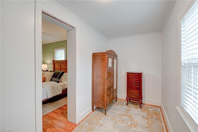 sitting room featuring light wood-type flooring, a wealth of natural light, crown molding, and baseboards