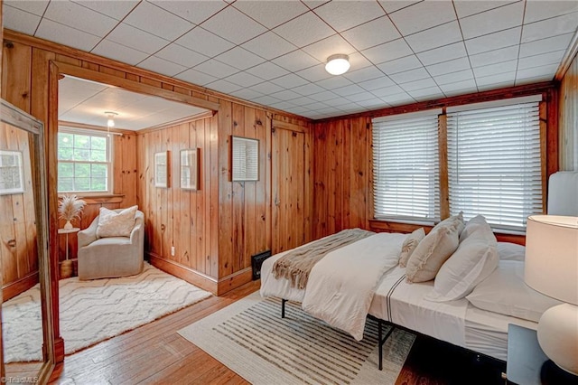 bedroom featuring baseboards, wood finished floors, and wood walls
