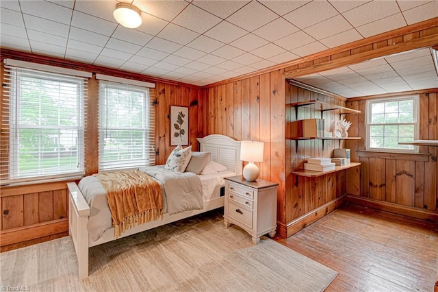 bedroom with light wood-type flooring, wooden walls, and baseboards