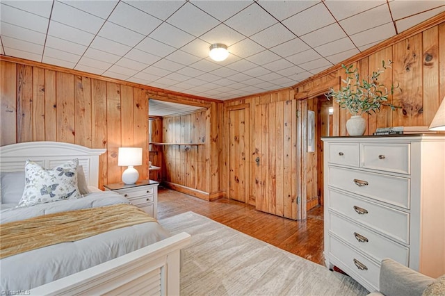 bedroom featuring baseboards, wooden walls, and wood finished floors