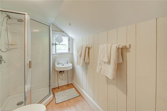 full bathroom featuring lofted ceiling, wood finished floors, and a shower stall