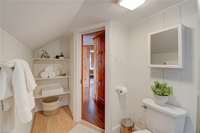 bathroom featuring vaulted ceiling, wood finished floors, toilet, and wood walls