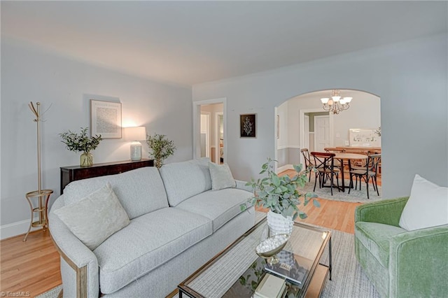 living area with light wood-type flooring, arched walkways, and a notable chandelier
