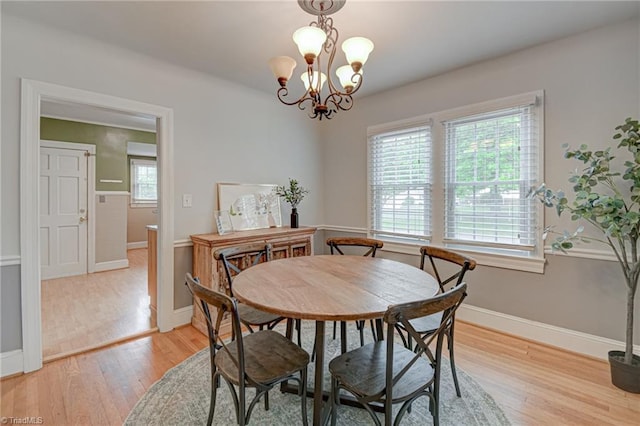 dining room with baseboards, an inviting chandelier, and light wood-style flooring