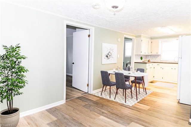 dining room with crown molding, light wood-type flooring, and a textured ceiling