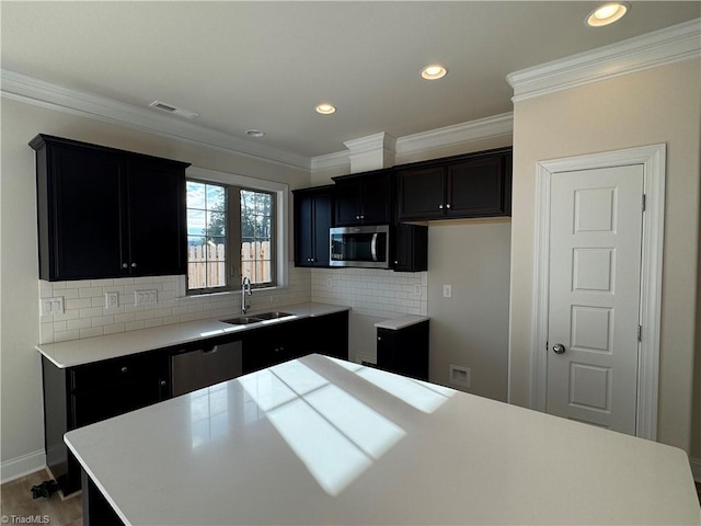 kitchen with sink, wood-type flooring, a kitchen island, stainless steel appliances, and backsplash