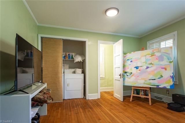 laundry room featuring washer and dryer, ornamental molding, hardwood / wood-style floors, and baseboards