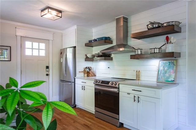 kitchen with open shelves, appliances with stainless steel finishes, wall chimney exhaust hood, light wood-type flooring, and white cabinetry