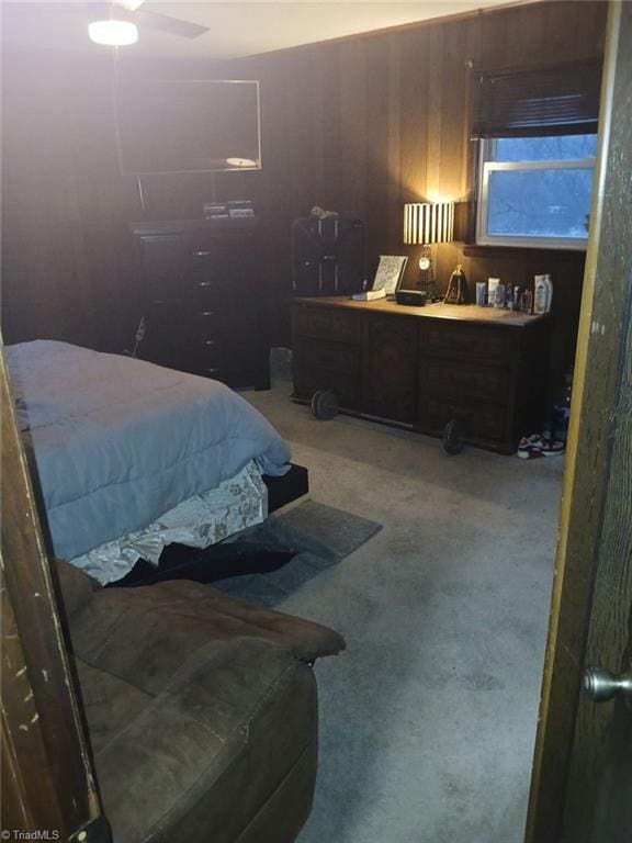 bedroom with ceiling fan, carpet floors, and wood walls