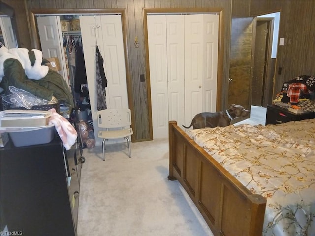 carpeted bedroom with wood walls and two closets