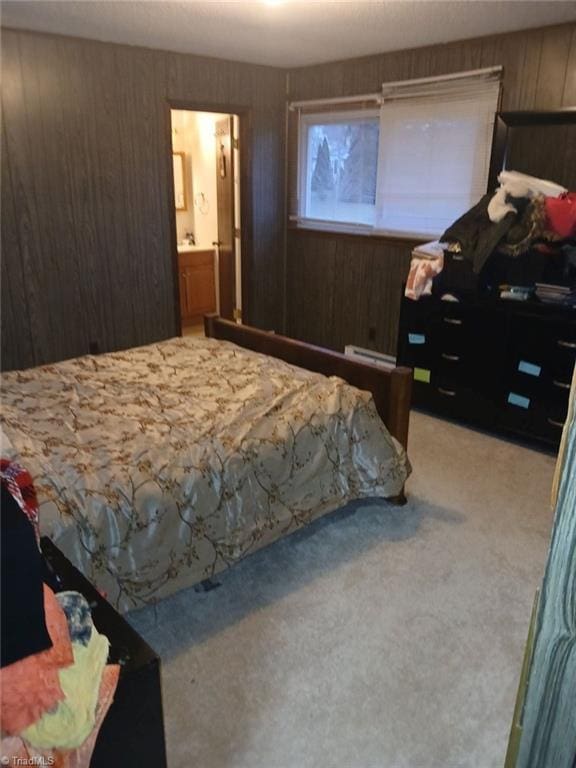 bedroom with baseboard heating, wood walls, carpet flooring, and ensuite bathroom