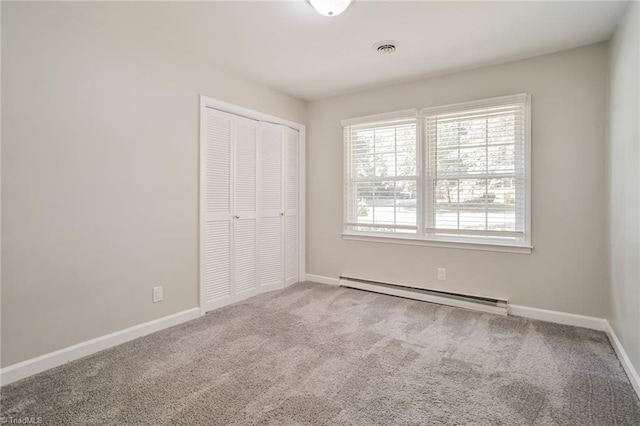 unfurnished bedroom with baseboard heating, a closet, and carpet floors